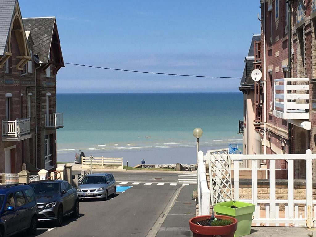 una calle con coches aparcados en la playa en Appartement vue mer, en Ault