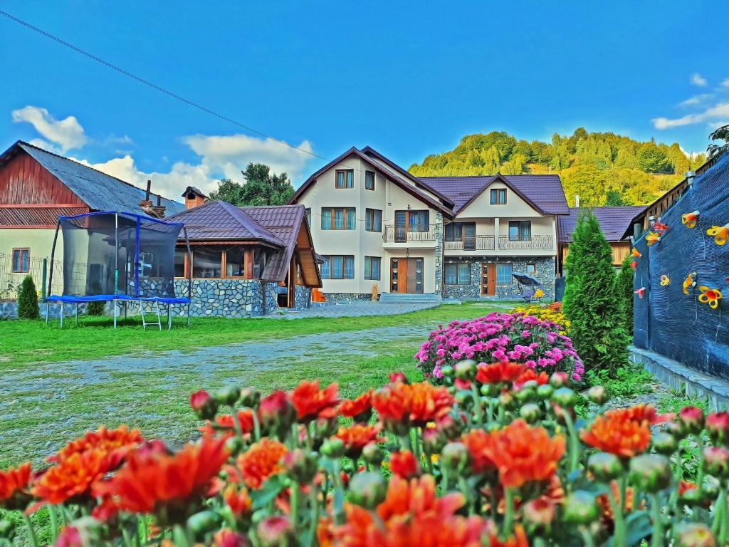 eine Gruppe von Häusern mit Blumen im Hof in der Unterkunft Pensiunea Dorul de Munte nr 222 in Rucăr