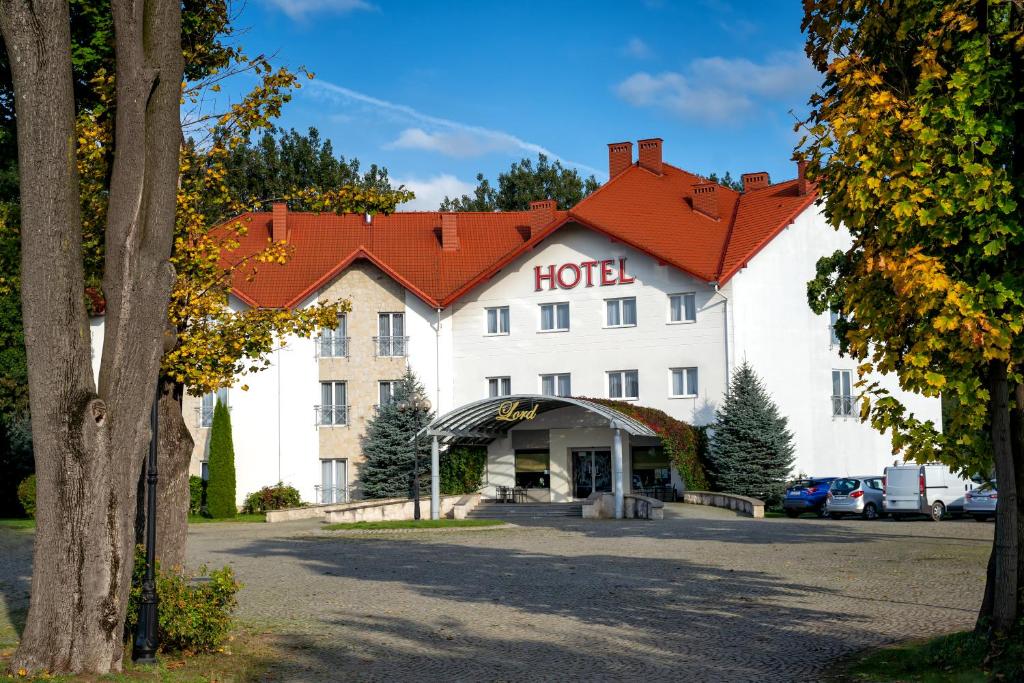 a hotel with a red roof in a parking lot at Hotel Lord Gorlice in Gorlice