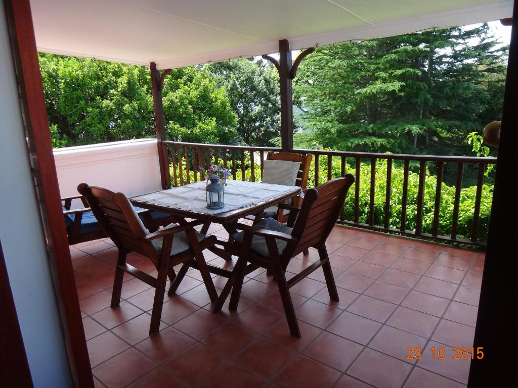 a table and chairs on a porch with a view of trees at Belvidere Garden Apartment in Knysna