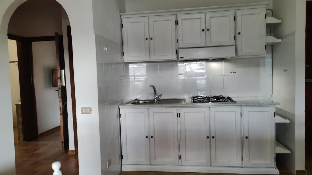 a kitchen with white cabinets and a sink at Residence Spiaggia Bianca in Golfo Aranci