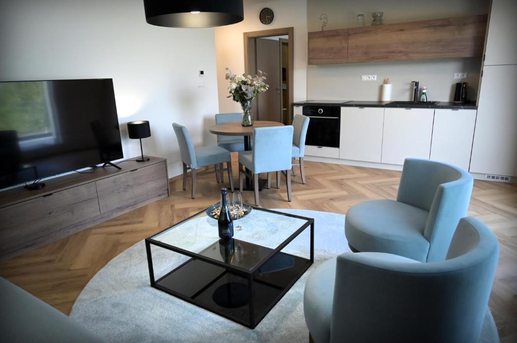 ein Wohnzimmer mit einem Tisch und Stühlen sowie eine Küche in der Unterkunft Apartmán Golfballs in Šajdíkove Humence