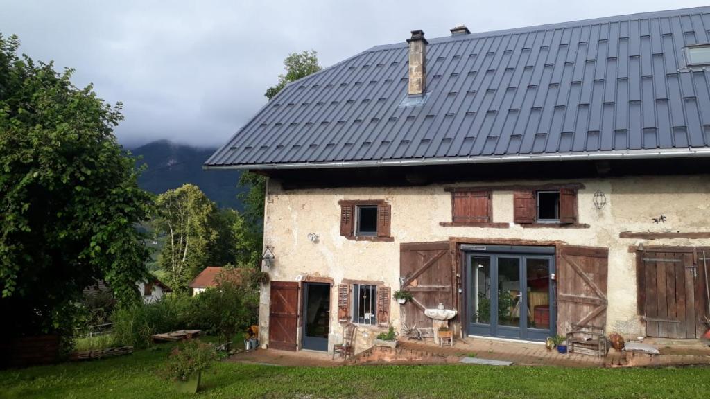 une maison ancienne avec un toit en métal dans l'établissement Les Praz, à Montcel