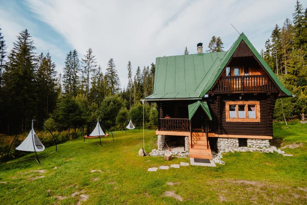 Cabaña de madera con techo verde y algunas tiendas de campaña en Chalupa Lieskovec en Tatranska Strba