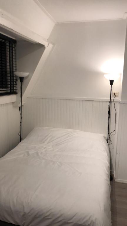 a white bed in a room with two lamps at Thomasloft in Oegstgeest