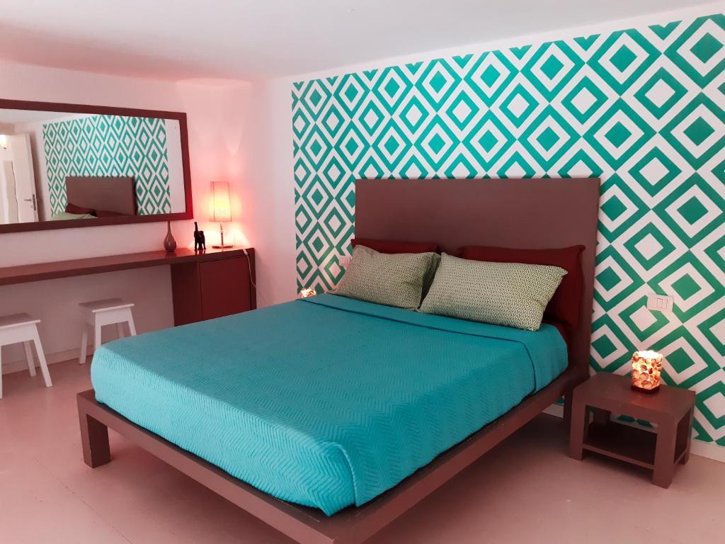 1 dormitorio con cama azul y espejo en App Rosanna, Estoril Beach, 2steps from the sea, Free Wi-Fi & AC, en Sal Rei