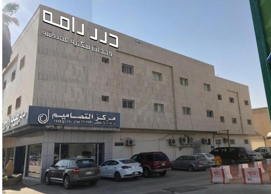 un grand bâtiment avec des voitures garées dans un parking dans l'établissement شقق درر رامه للشقق المخدومة 12, à Riyad