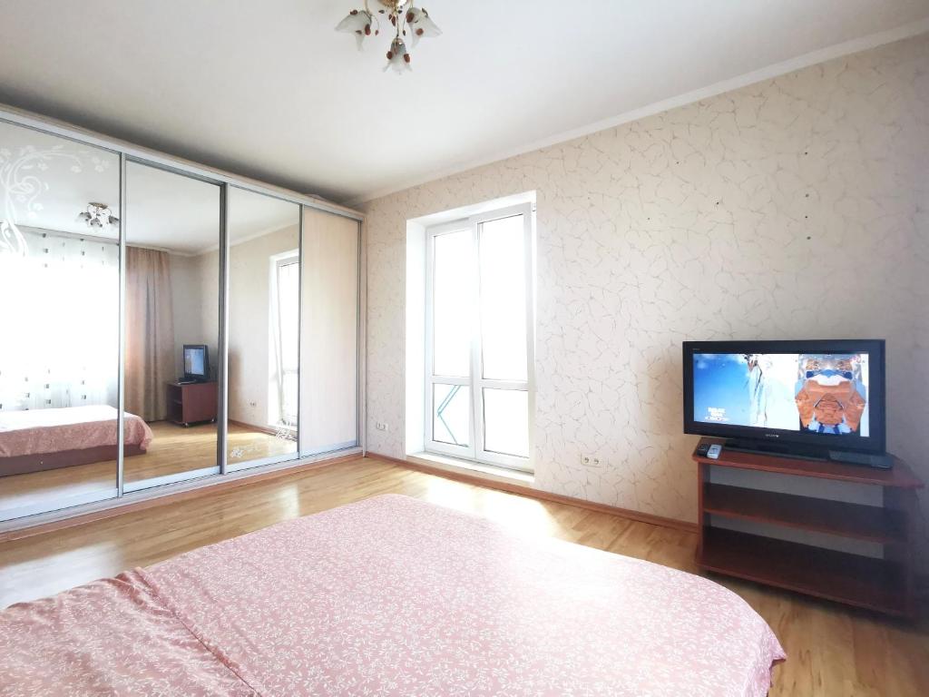 a bedroom with a tv and a bed and a window at Lavina mall apartments 4 in Sumy