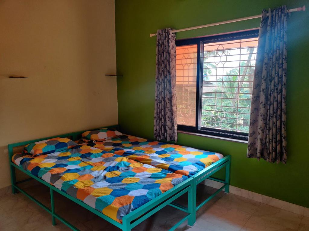 a bed in a green room with a window at Sakhey Homestay in Ratnagiri