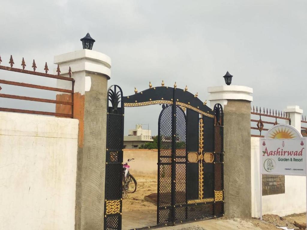 a gate to a compound with a bike behind it at Aashirwad Garden & Resort in Pilani