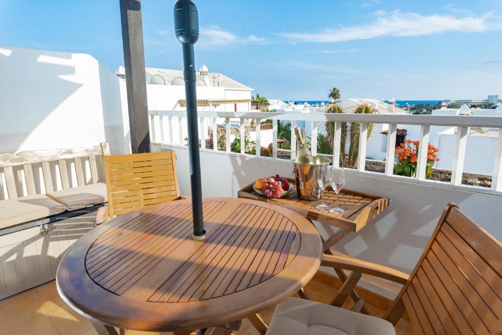 y balcón con mesa y sillas de madera. en Bliss -Panoramic views- en Costa Teguise