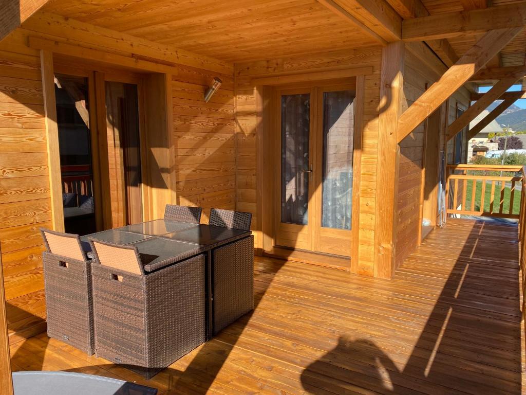 Charmant logement à Serre Chevalier في Puy-Saint-Pierre: شرفة كابينة خشب مع طاولة وكراسي