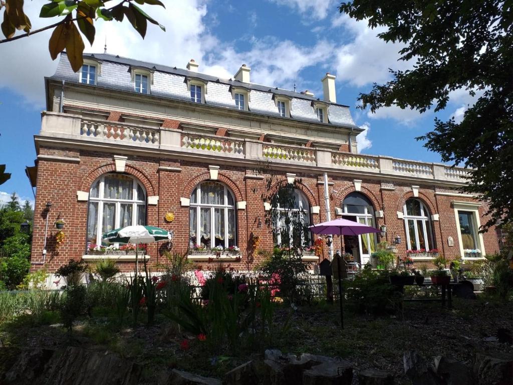 een groot bakstenen gebouw met een paraplu ervoor bij VILLA LES CAMELIAS in Fontaine-lès-Vervins