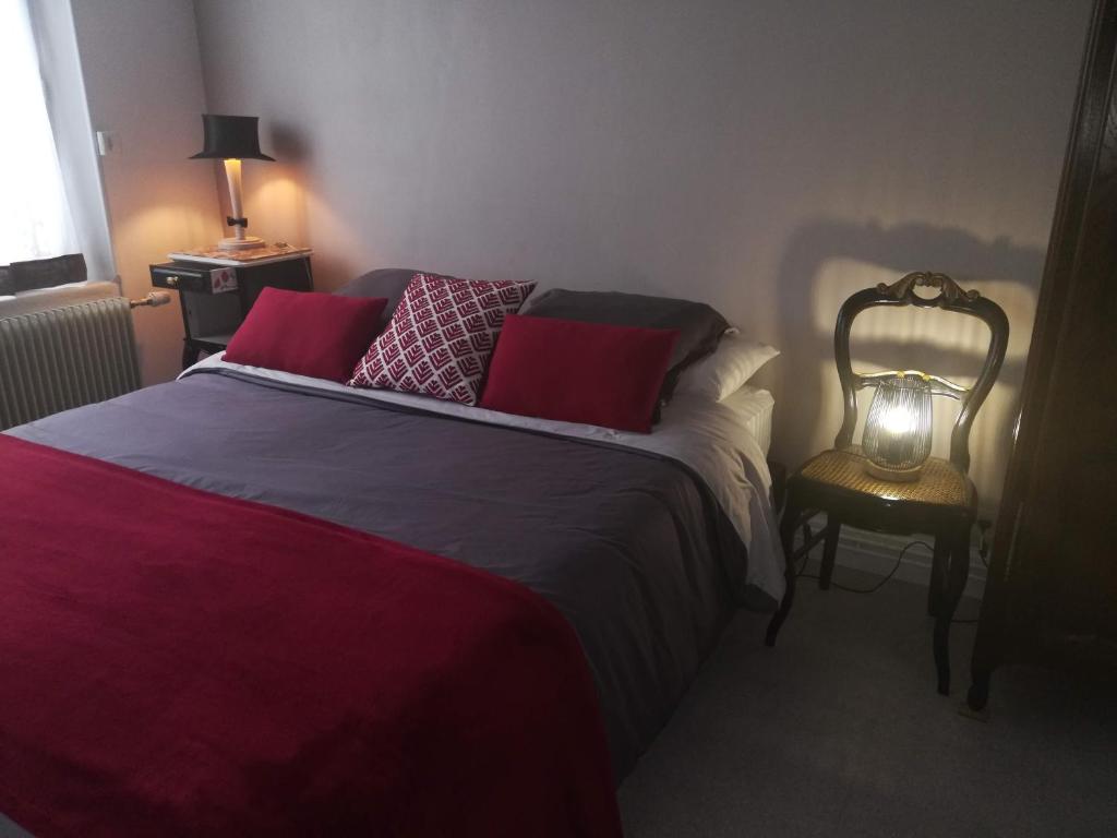 een slaapkamer met een bed en een lamp op een stoel bij Le Coq en pâte in Romilly-sur-Seine