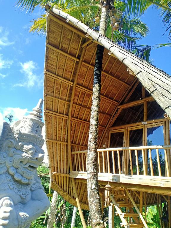 a bamboo house with a statue in front of it at Jero Tumbuk Private Villa in Selat