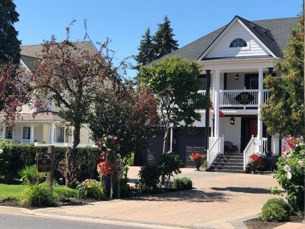 ein weißes Haus mit einer roten Tür und Bäumen in der Unterkunft Casa Blanca Boutique Bed & Breakfast in Niagara on the Lake