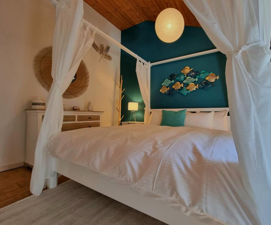 1 dormitorio con cama blanca con dosel y pared azul en Fischerhüsli directly on lake Thun, en Därligen