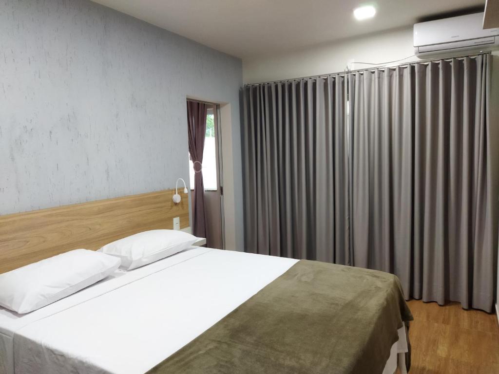 een slaapkamer met een groot wit bed en een raam bij Chapada Confort Flats in Alto Paraíso de Goiás