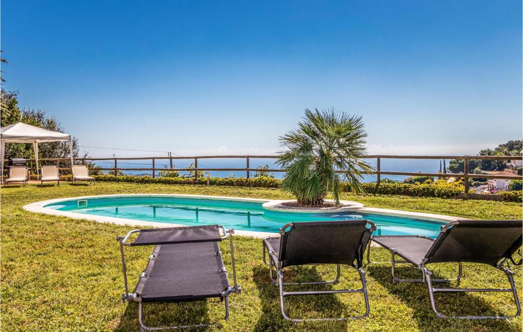 uma piscina com duas cadeiras e uma palmeira em Cozy Home In Sant Cebri De Vallalta With House Sea View em Sant Cebrià de Vallalta
