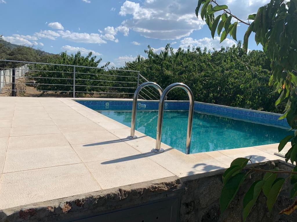 una piscina con dos pasamanos de metal al lado en Casa Rural Canchal Madroñeras ***, en El Torno