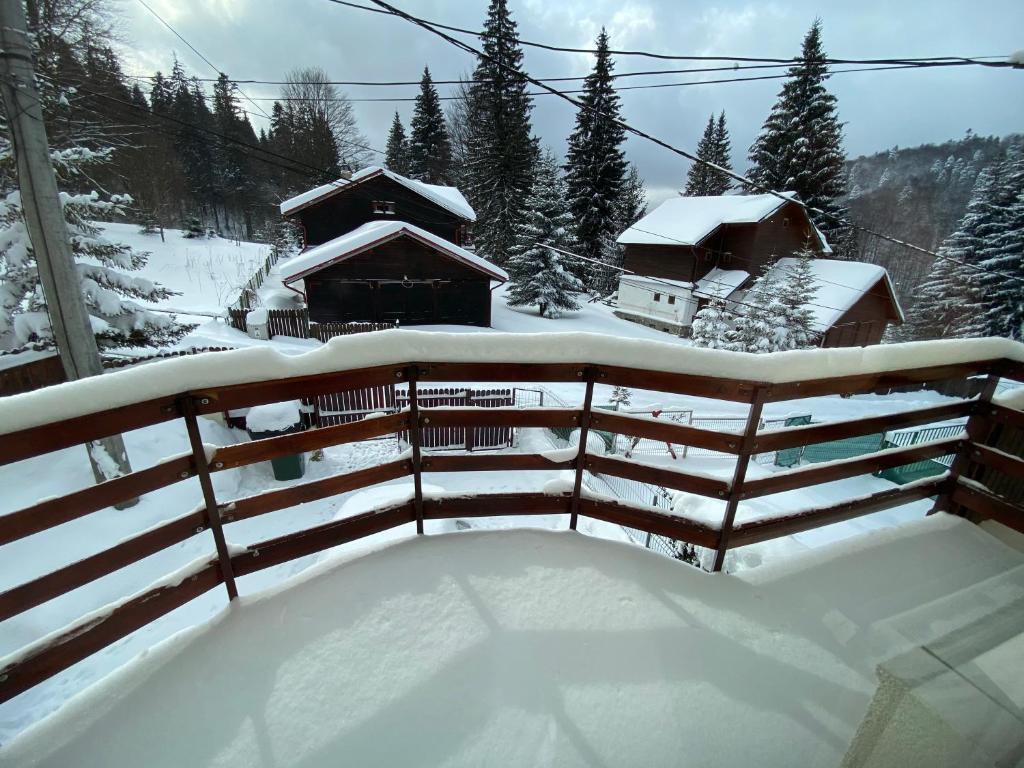 una valla cubierta de nieve frente a los edificios en Vila Amira Predeal, en Predeal