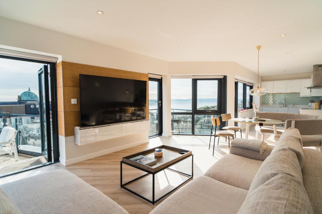 a living room with a couch and a tv and a table at Westcliff Penthouse in Bournemouth