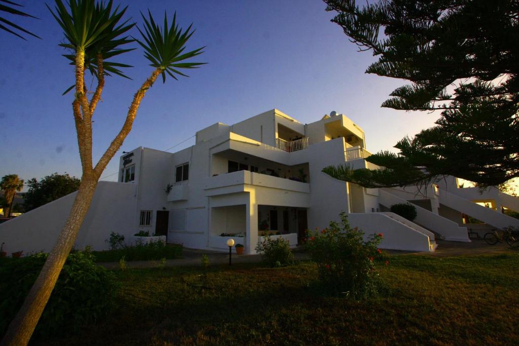 una casa blanca con una palmera delante de ella en Eftihia Apartments en Cos