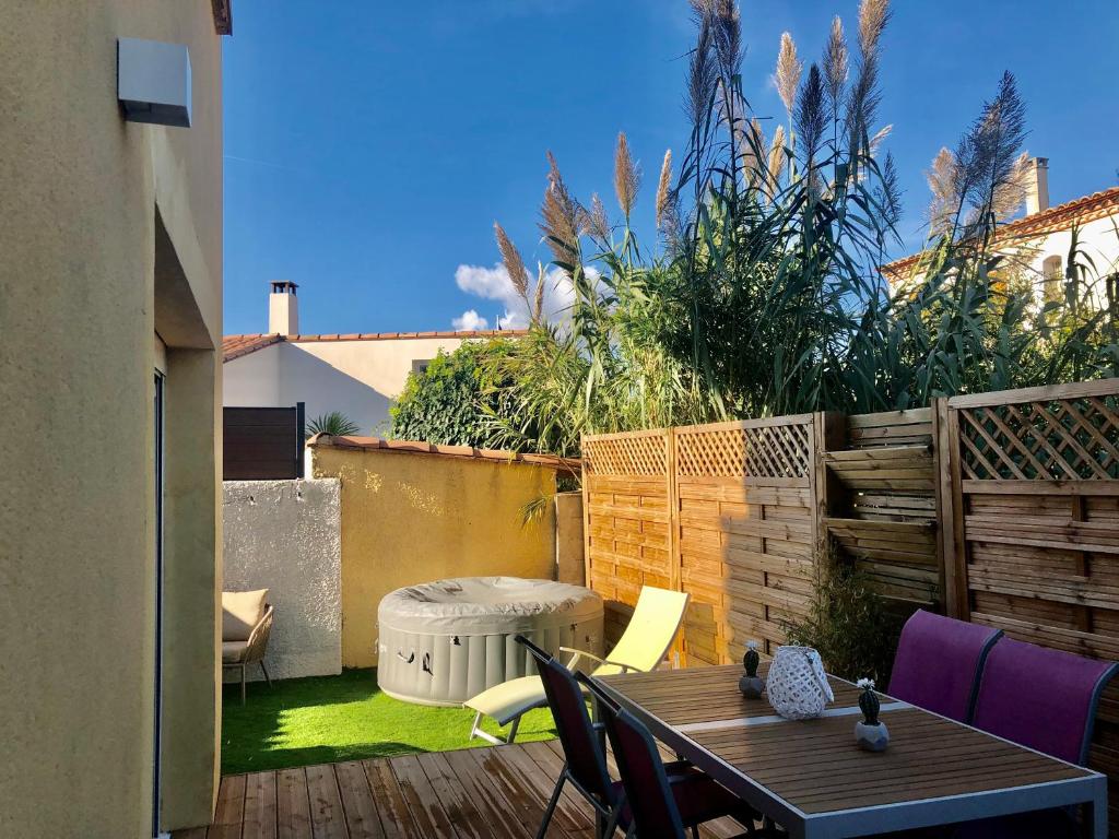 patio con tavolo e sedie su una terrazza di Villa 3 pièces avec jacuzzi privé a Pérols