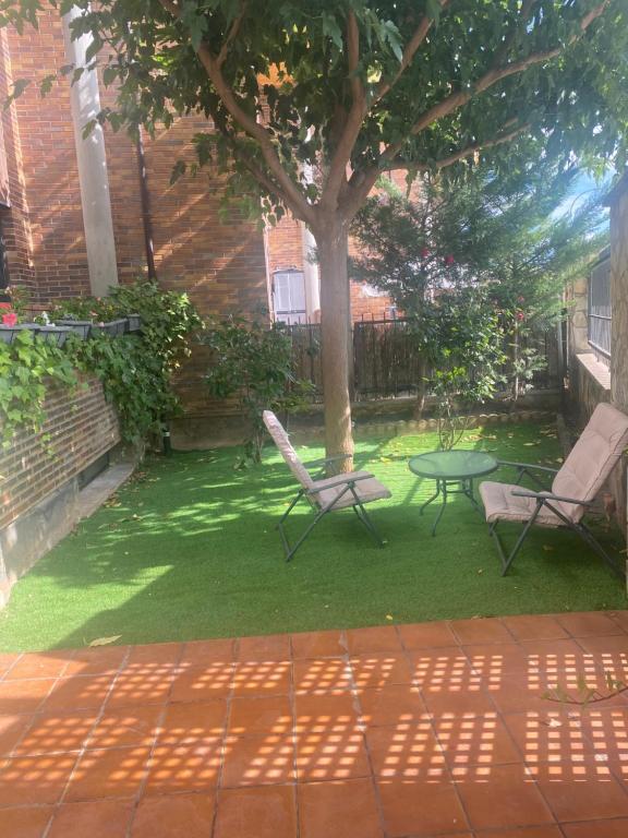 un patio con 2 sillas, una mesa y un árbol en Las Moreras, en Calatayud