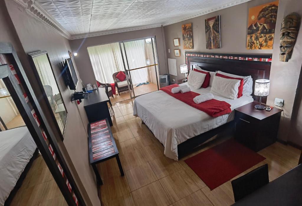 1 dormitorio con 1 cama grande con manta roja en Blyde Lodge, en Graskop