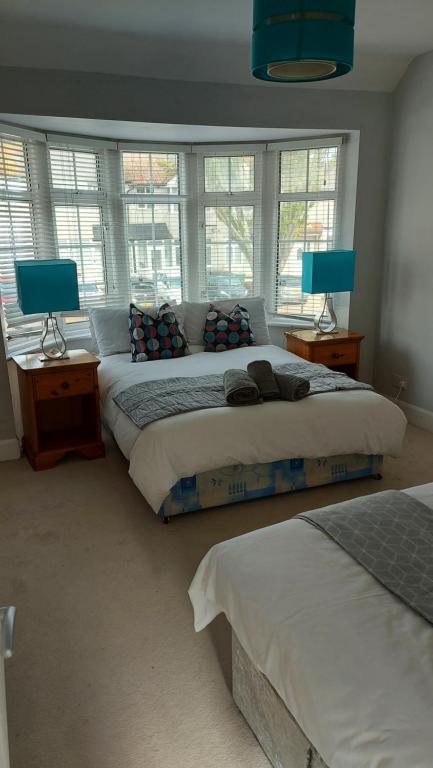 two beds in a bedroom with two lamps and windows at I Dwell Sidcup House in Welling