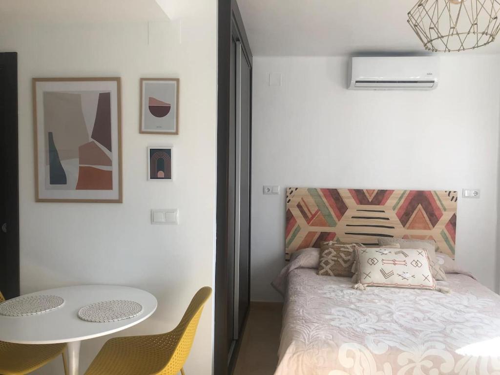 een kleine slaapkamer met een bed en een tafel bij Apartmento studio boho a 1 minuto del puerto y la playa! in Jávea