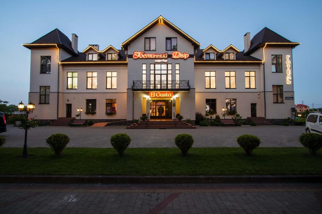 a large white building with a neon sign on it at Hostynnyy Dvir in Stryi