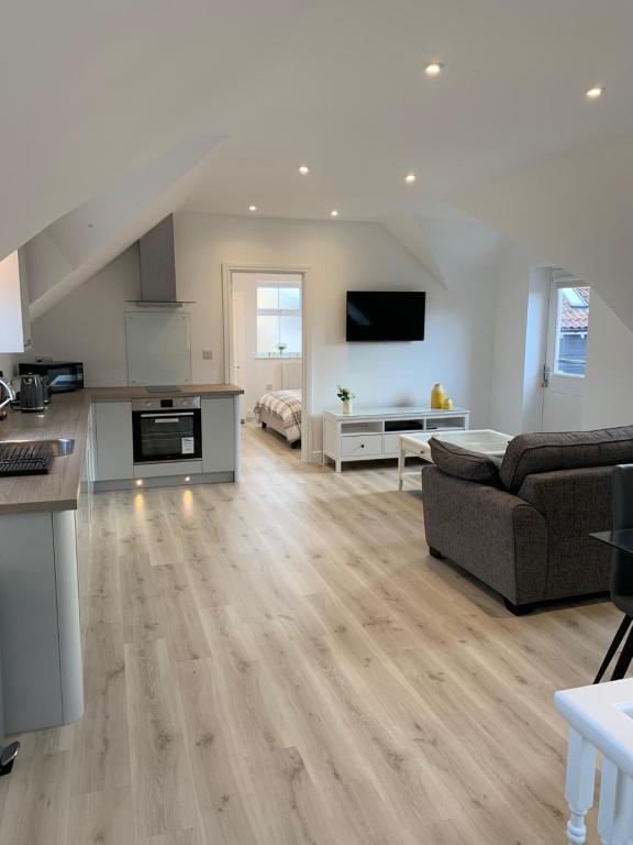 a large living room with a couch and a kitchen at Peartree Lodge in Cambourne