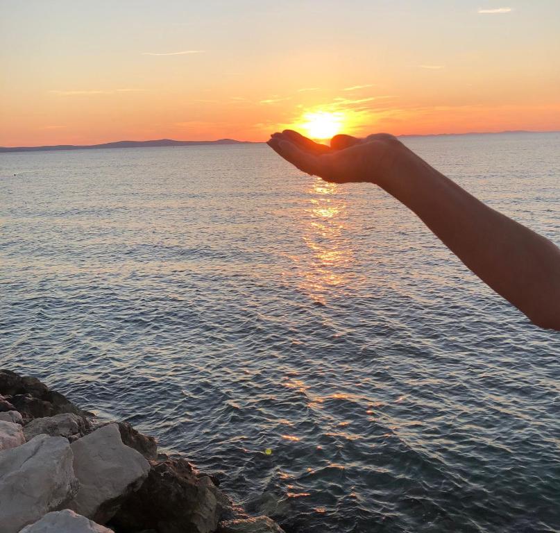 a person is standing on the beach watching the sunset at Apartman Lili in Zaton