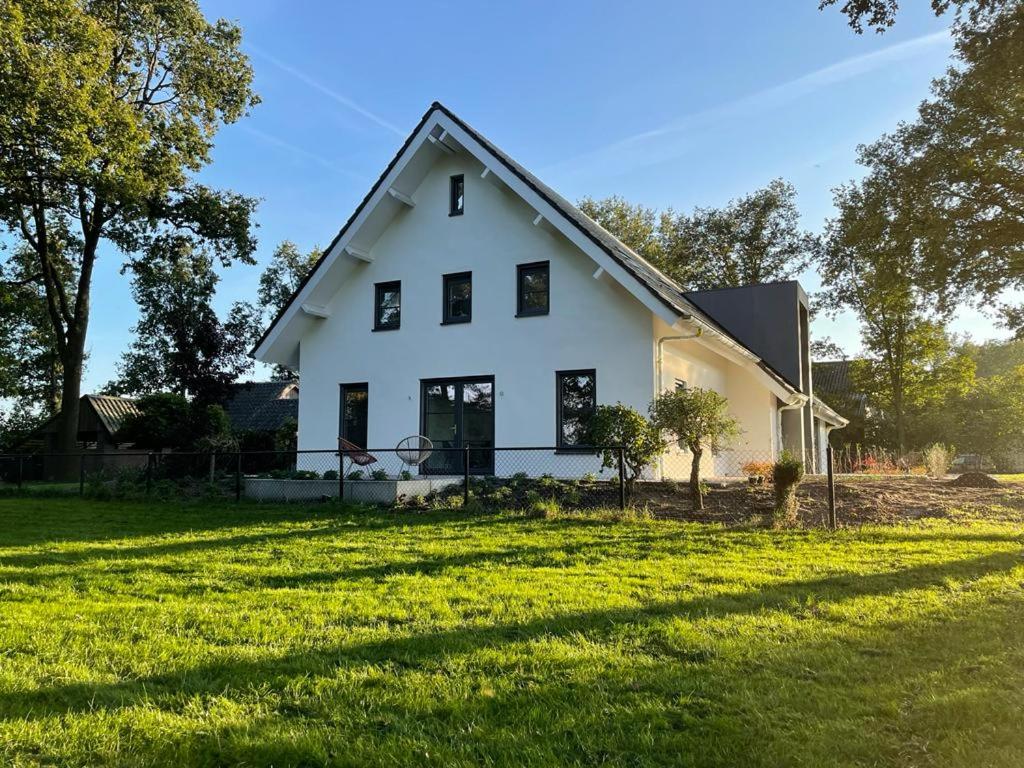een wit huis met een groot grasveld bij 't Huis van de Buren - Drie unieke boerderijkamers in Lutten in Lutten