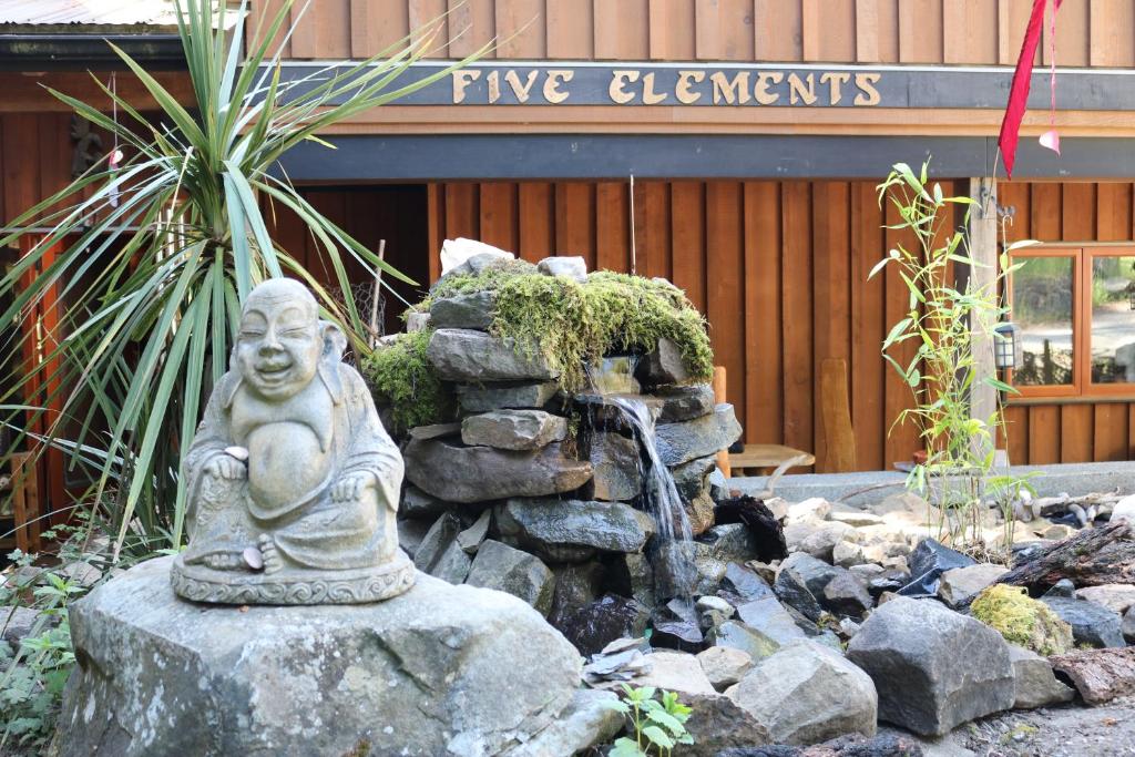 a statue in a garden in front of a building at Five Elements Lodge B&B with Outdoor Spa in Fernwood