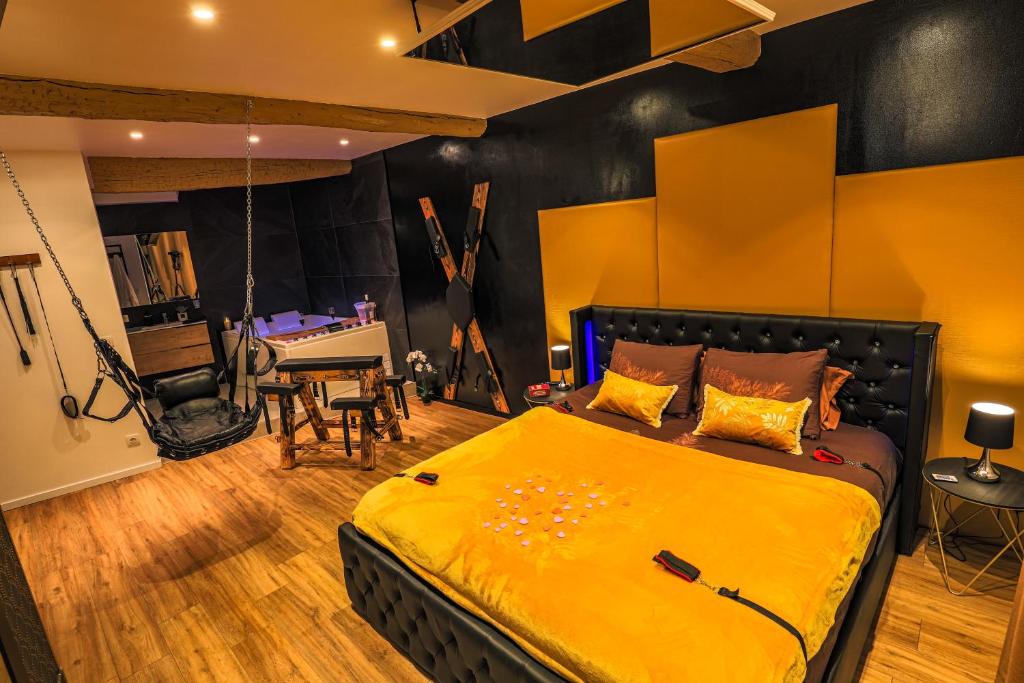 a bedroom with a bed with a yellow blanket at La loveroom bdsm grassoise "La chambre des désirs" in Grasse