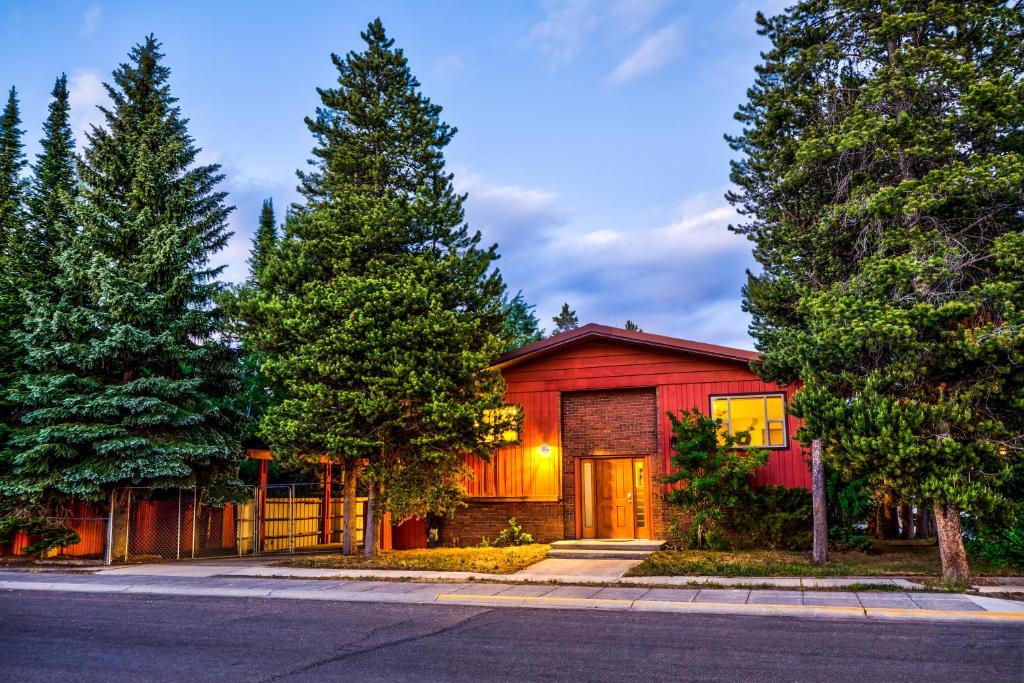 a red house on a street with trees at Geyser Getaway in West Yellowstone