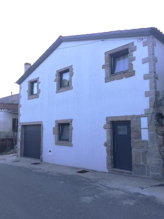 een wit gebouw met twee deuren en twee ramen bij Casa das Bonecas in Mangualde