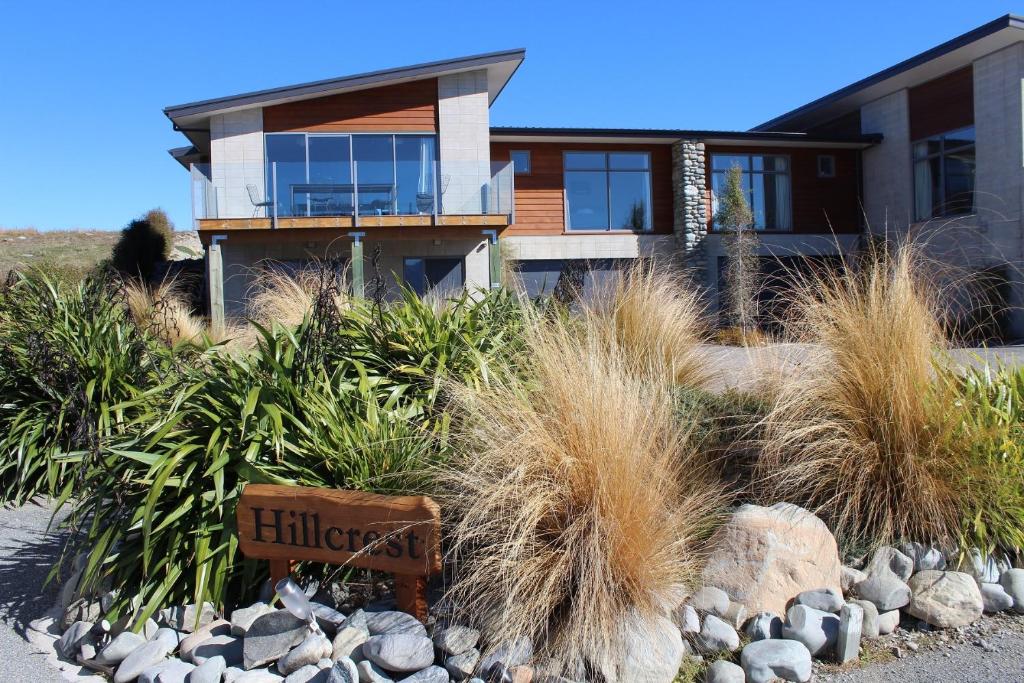 a house with tall grass and rocks in front of it at Hillcrest Lodge A - Lake Tekapo in Lake Tekapo