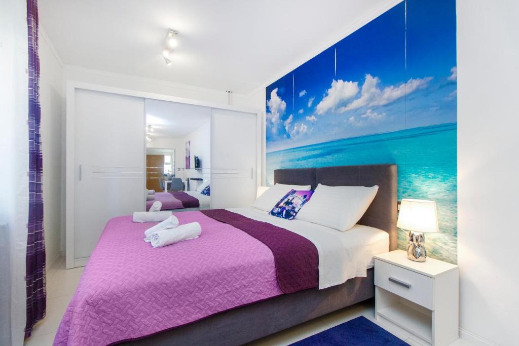 sypialnia z fioletowym łóżkiem z obrazem na ścianie w obiekcie Apartment Seaside, free parking w Szybeniku