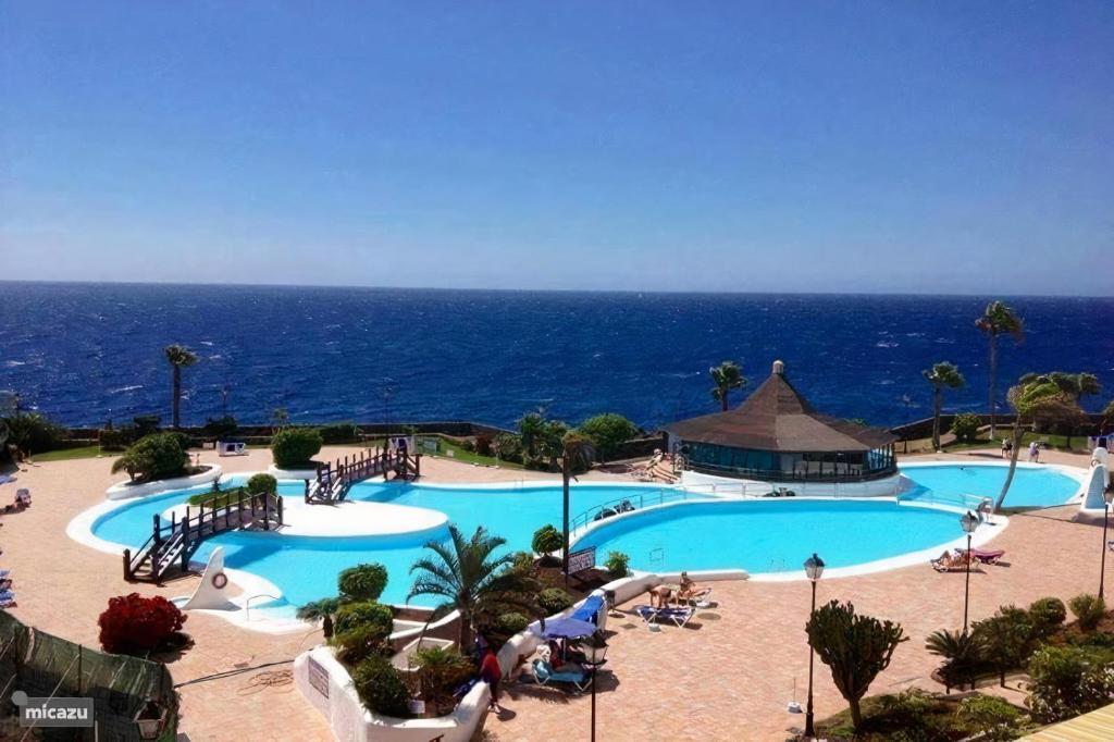 a large swimming pool with the ocean in the background at Rocas del Mar Holiday in Costa Del Silencio