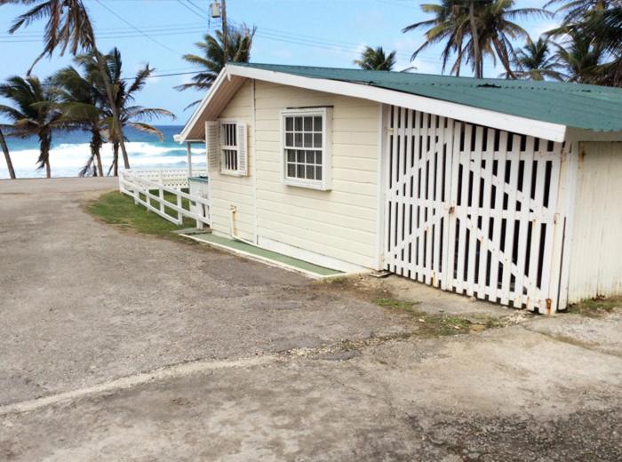 un pequeño edificio blanco con una puerta y palmeras en Rest Haven Beach Cottages, en Saint Joseph