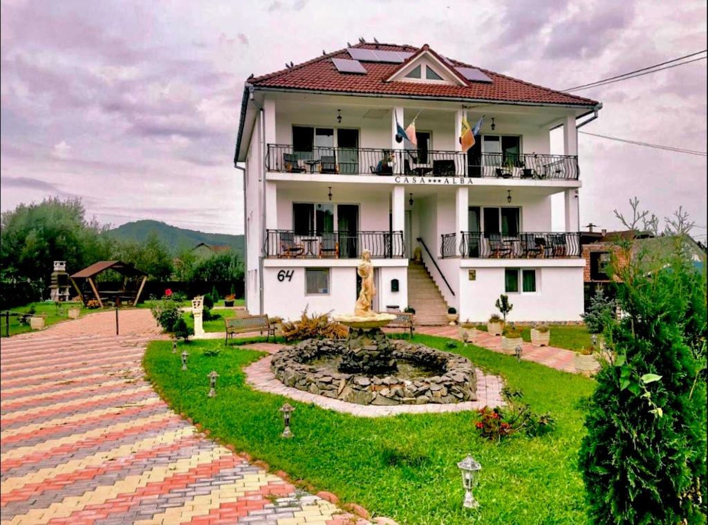 a house with a garden and a fountain in front of it at Pensiunea Casa Albă in Beclean
