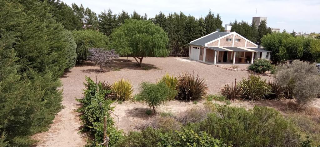 una casa en medio de un jardín con árboles en Quinta El Descanso en Puerto Madryn