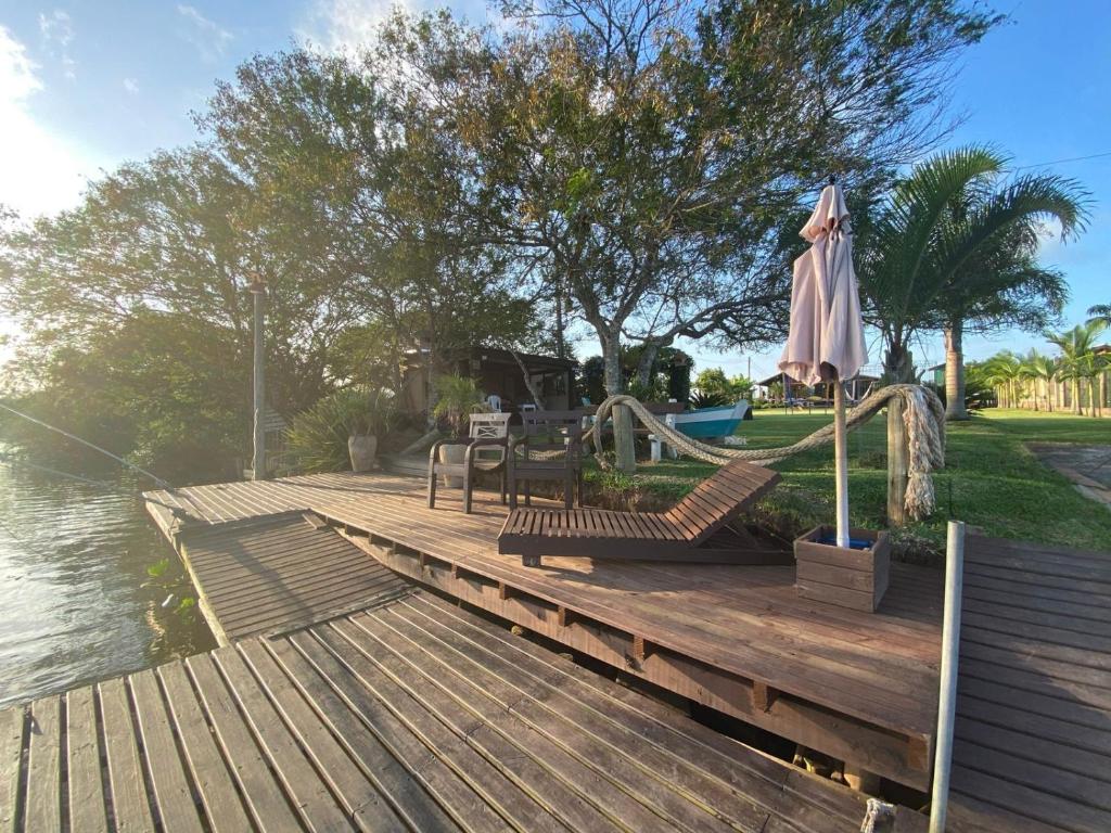 a wooden dock with an umbrella and a playground at Pousada Refúgio Náutico in Passo de Torres