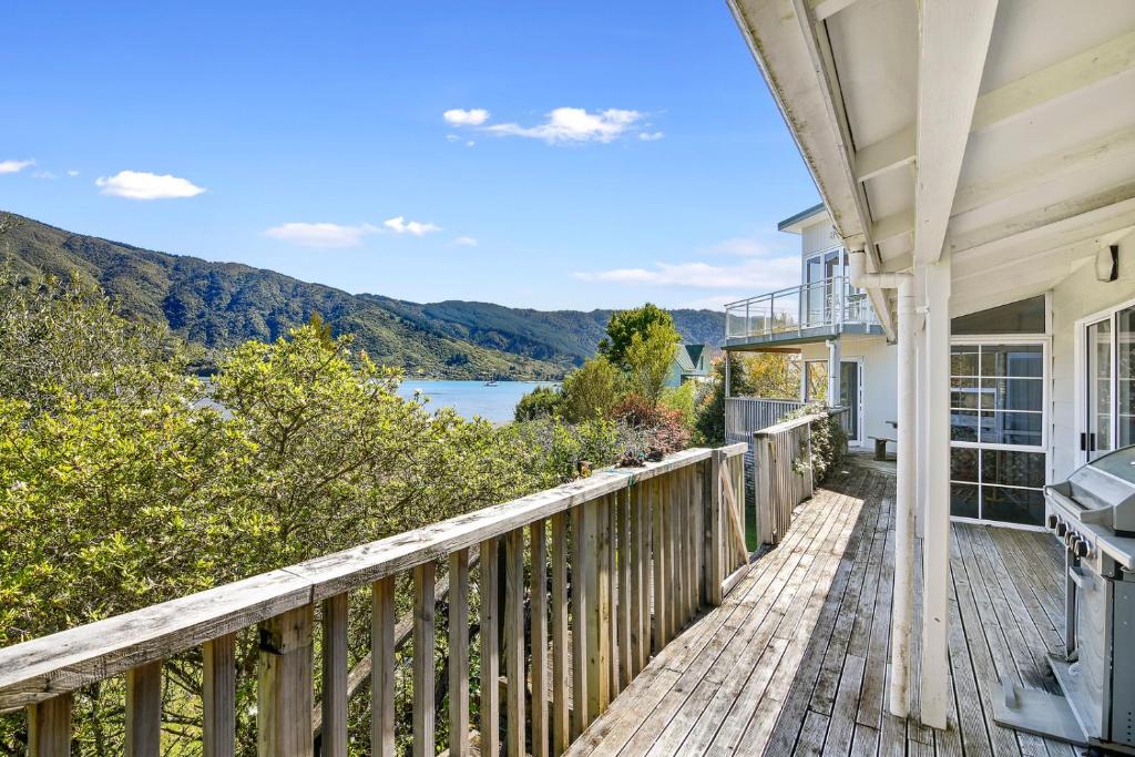 a house with a deck with a view of the water at Millard House - Marlborough Sounds in Grove
