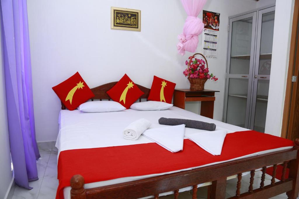 sypialnia z łóżkiem z białymi i czerwonymi poduszkami w obiekcie Evening Star Guest Inn w mieście Kandy
