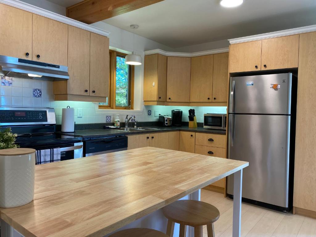eine Küche mit einem Kühlschrank aus Edelstahl und Holzschränken in der Unterkunft Chalet «L'Autrichien» de Charlevoix in Petite-Rivière-Saint-François
